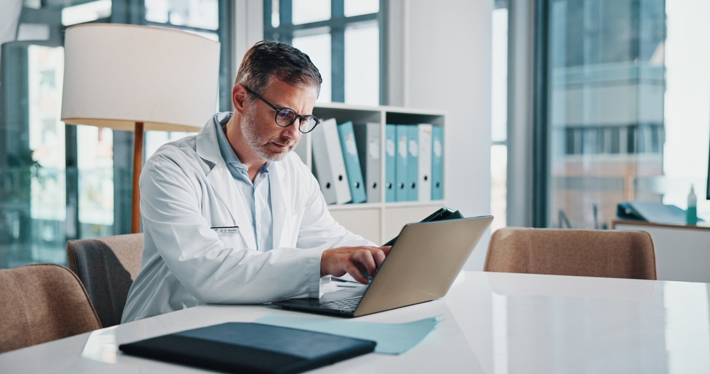 Confirming Your MiDOG Practice Contacts Veterinarian using a laptop to review and confirm practice contact information during MiDOG onboarding.